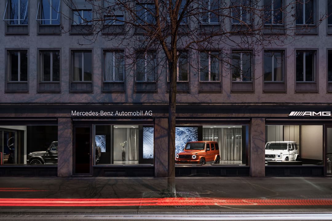 Façade du magasin Stars@Mercedes-Benz à Zurich, avec véhicules haut de gamme exposés en vitrines, dont un SUV orange et une berline blanche