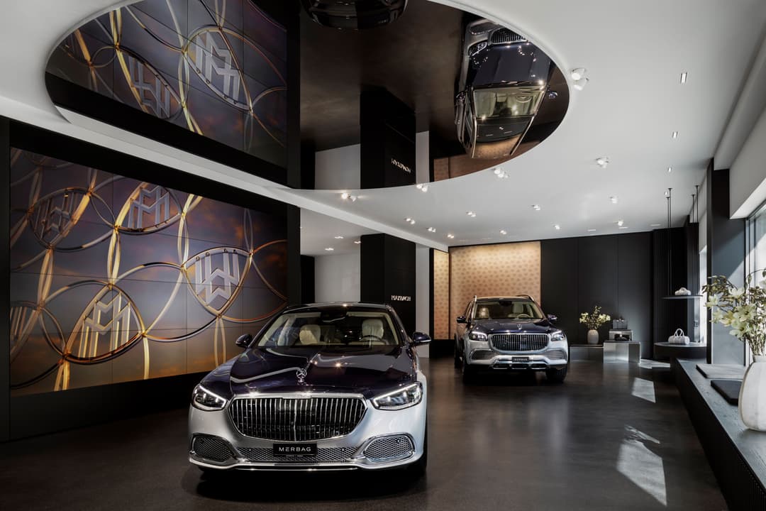 Intérieur du magasin Stars@Mercedes-Benz de Zurich avec deux berlines de luxe exposées, écrans vidéo aux murs et éclairage épuré