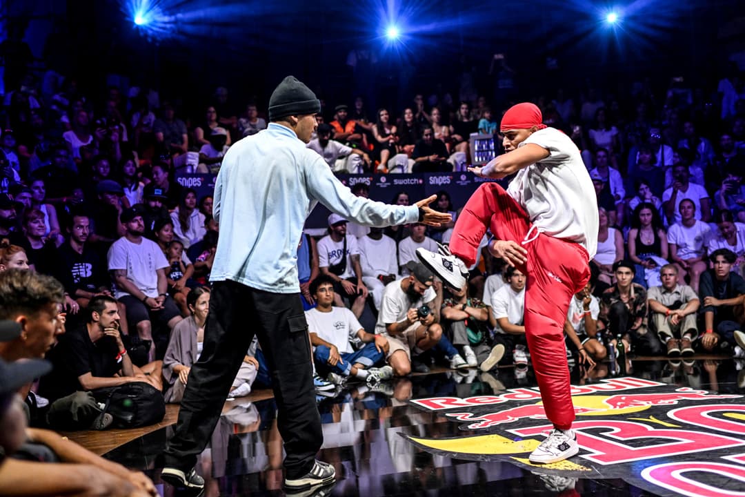 Deux danseurs de breakdance face à face lors d'une battle à la Halle 622, entourés d'un public nombreux éclairé de lumières bleues