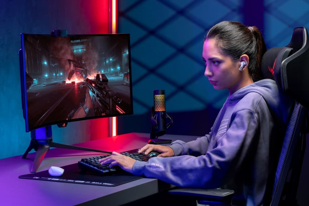 Gamer portant les écouteurs ROG Cetra True Wireless SpeedNova, assis devant un écran affichant un jeu de tir