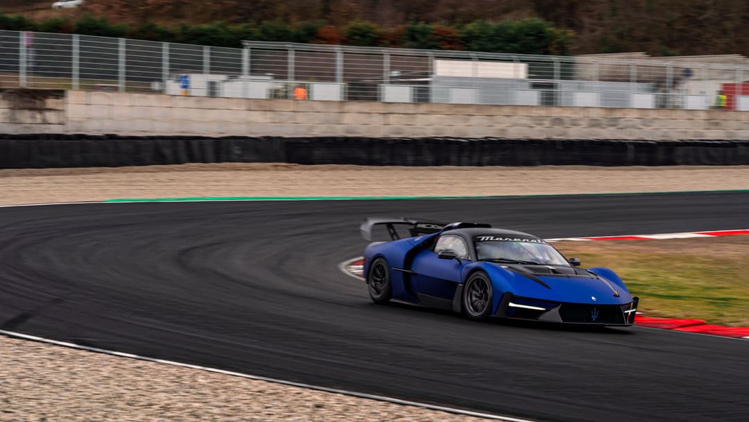 Maserati MCXtrema bleu en virage serré sur circuit de course avec ligne rouge au sol