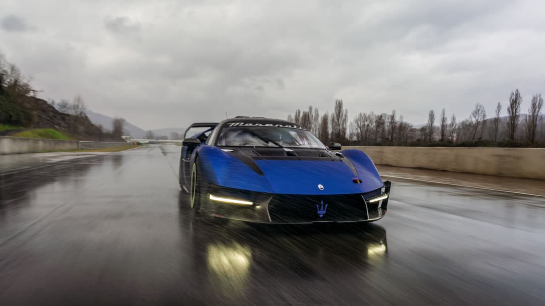 Maserati MCXtrema bleu et noir en mouvement sur une piste mouillée, paysage montagneux en arrière-plan