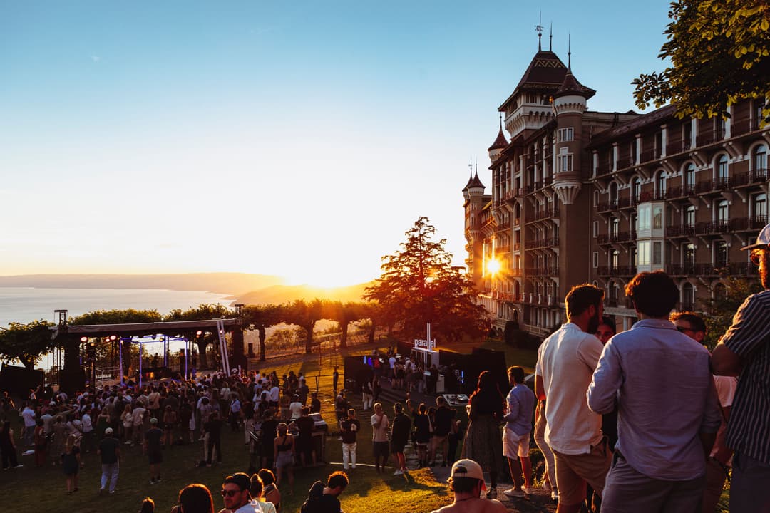 Foule lors d'un concert du Montreux Jazz Festival au coucher du soleil, avec le Montreux Palace Hotel en arrière-plan