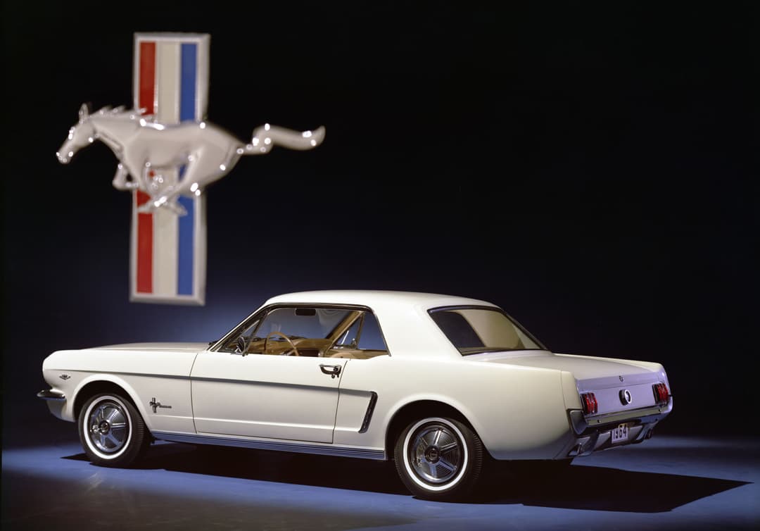 Ford Mustang blanche de profil avec logo du cheval et bandes tricolores au-dessus, fond noir