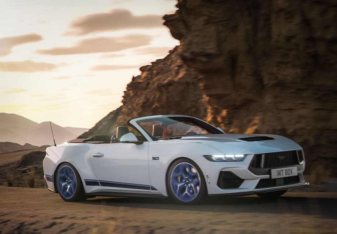 Ford Mustang California Special cabriolet blanc avec bandes bleues, garée face à une falaise rocheuse au coucher du soleil