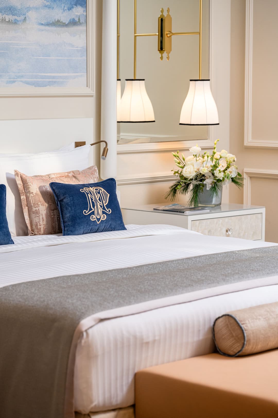 Chambre rénovée du Fairmont Le Montreux Palace avec lit aux oreillers bleus et roses, miroir suspendu et vue du lac Léman par la fenêtre