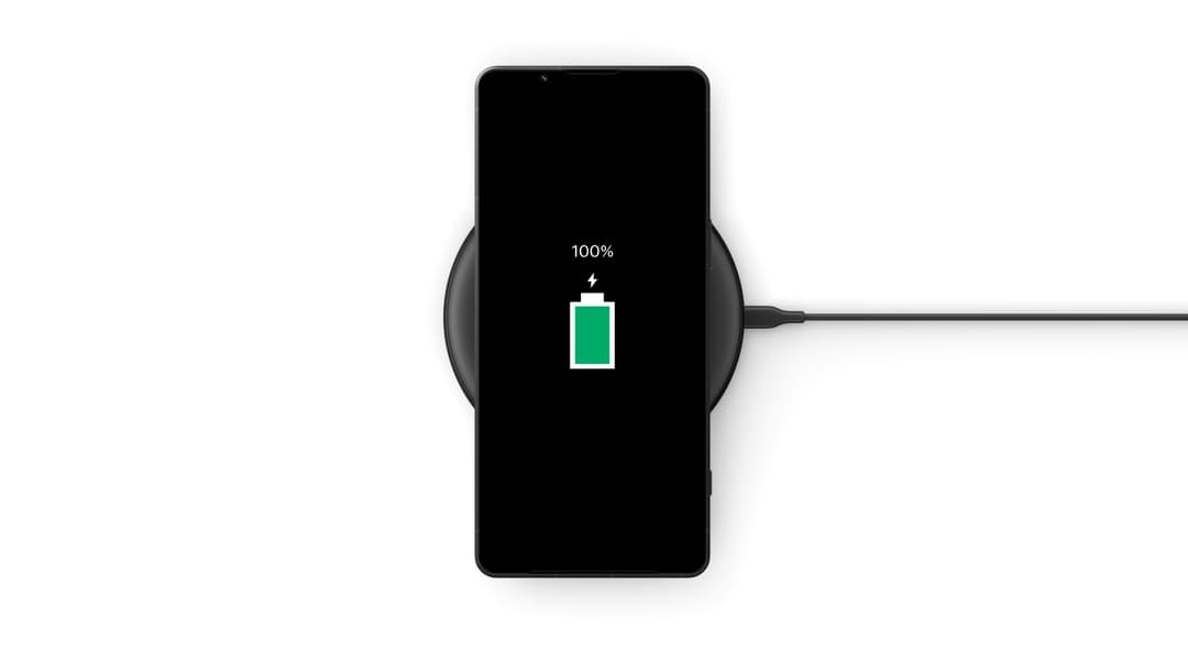 Sony Xperia 1 VI posé sur un chargeur sans fil, écran affichant une batterie verte à 100%
