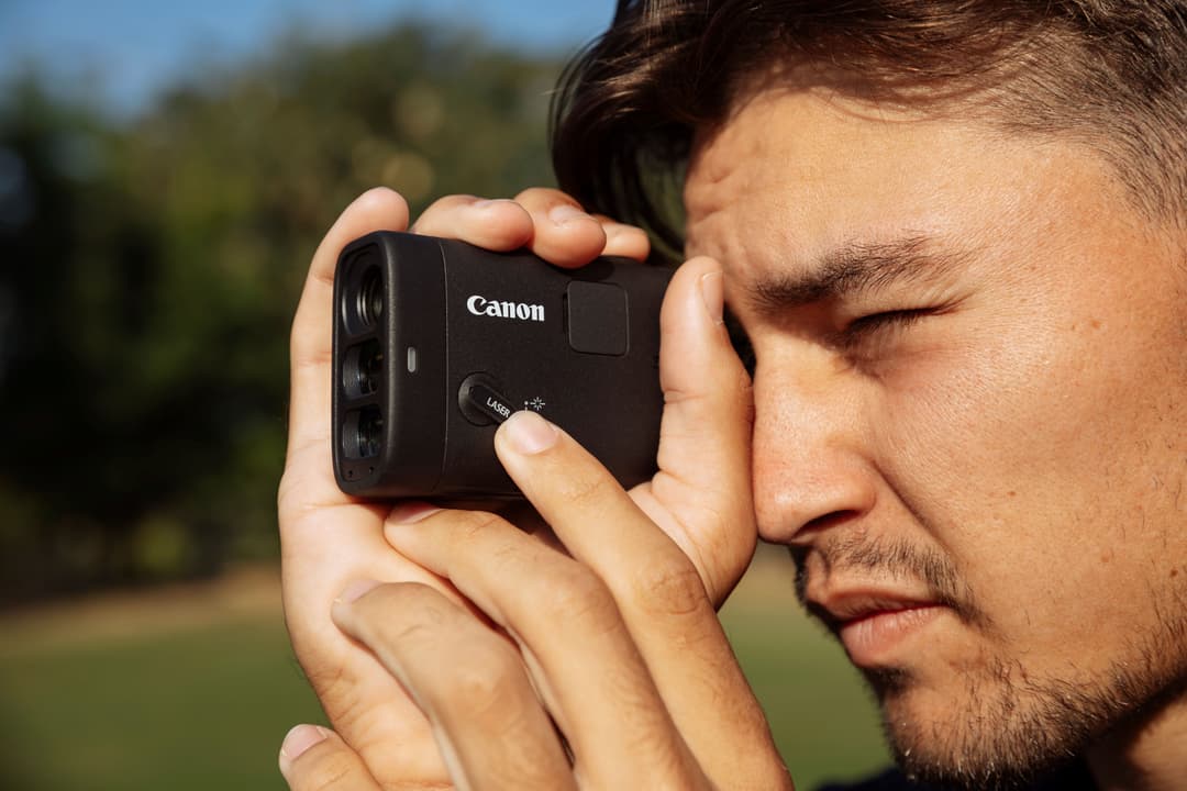 Golfeur utilisant un télémètre laser compact Canon noir avec appareil photo intégré sur un parcours de golf