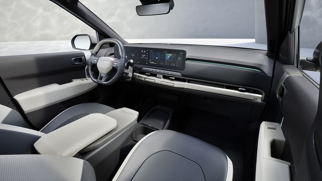 Intérieur de la Kia EV3 avec tableau de bord moderne, sièges bicolores noir et blanc en tissu recyclé, et grand écran tactile