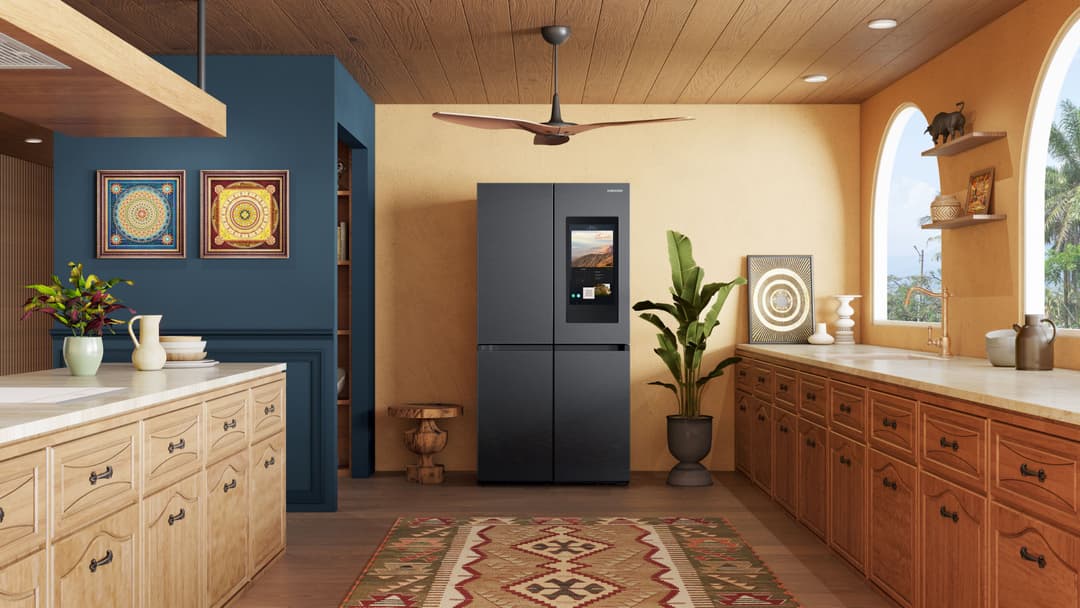 Réfrigérateur Samsung noir quatre portes avec écran tactile intégré, au centre d'une cuisine aux murs ocre et boiseries blondes