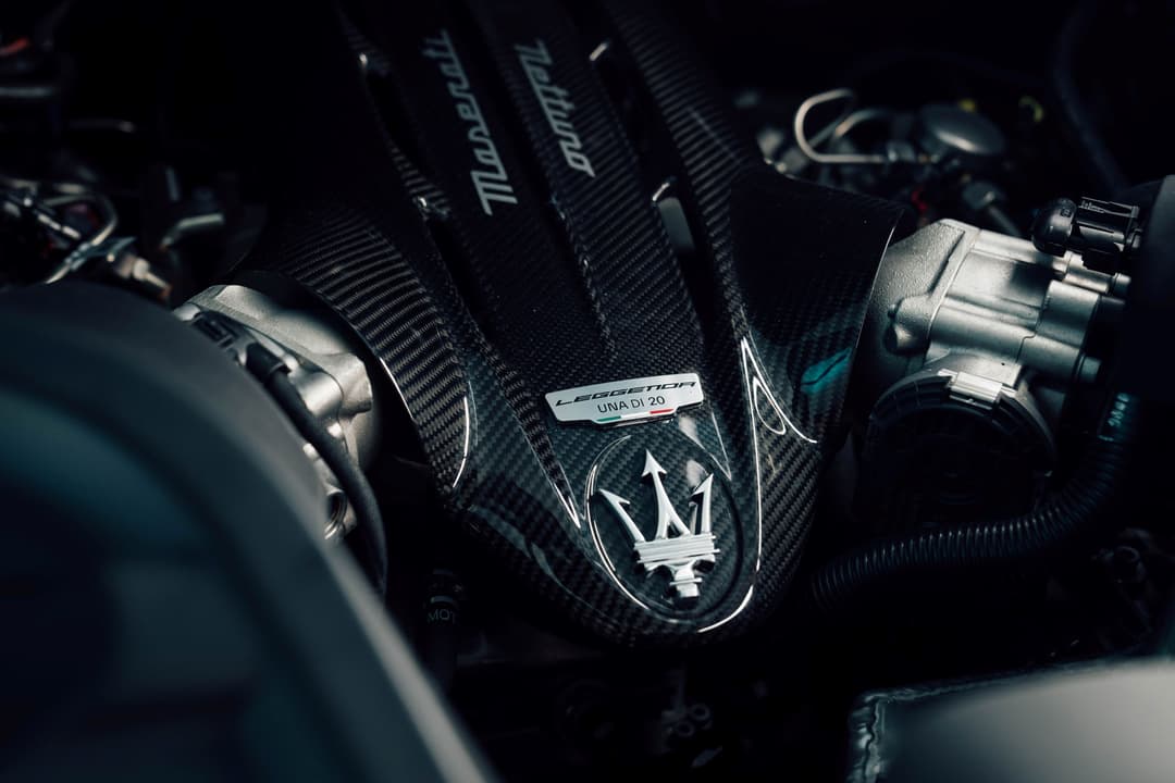 Moteur Nettuno de Maserati avec badge « UNA DI 20 » et trident chromé, entouré de tubulures en carbone noir
