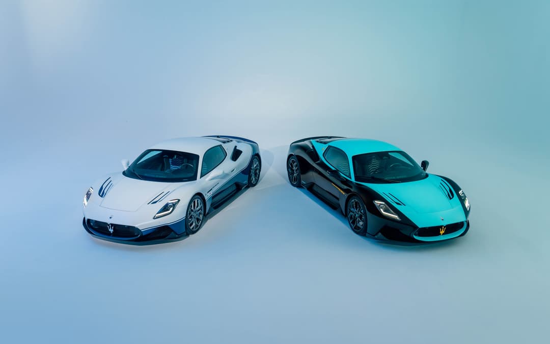 Deux Maserati MC12 Anniversaire, l'une blanche et l'autre turquoise, présentées de face sur fond bleu ciel
