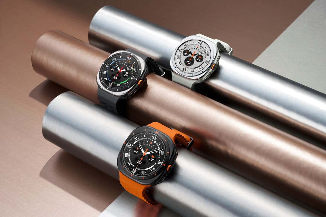 Trois Samsung Galaxy Watch Ultra posées sur des cylindres métalliques : une à cadran noir, une à cadran blanc et une à bracelet orange