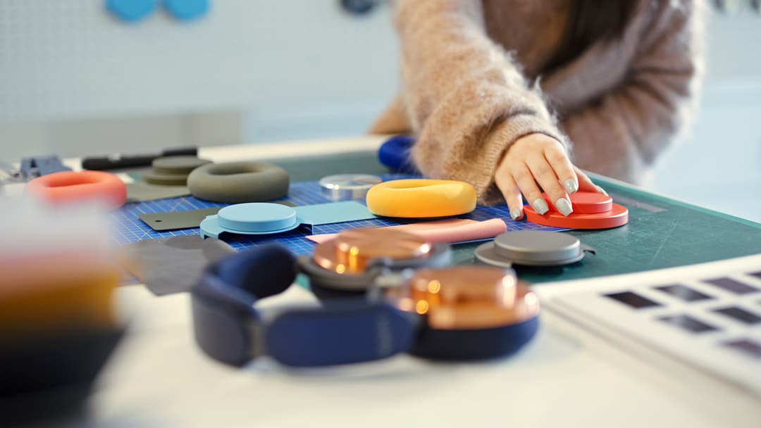 Casque audio Dyson OnTrac aux coloris variés posé sur une surface, avec des accessoires présentant différentes teintes