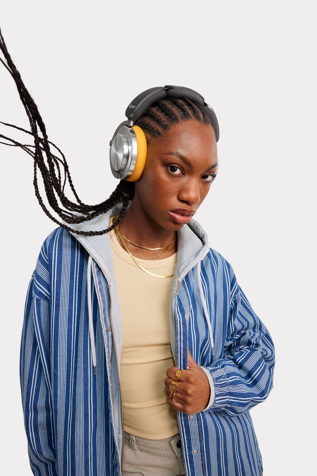 Casque audio Dyson OnTrac noir et jaune porté par une femme, avec coussins en mousse et bras pivotants