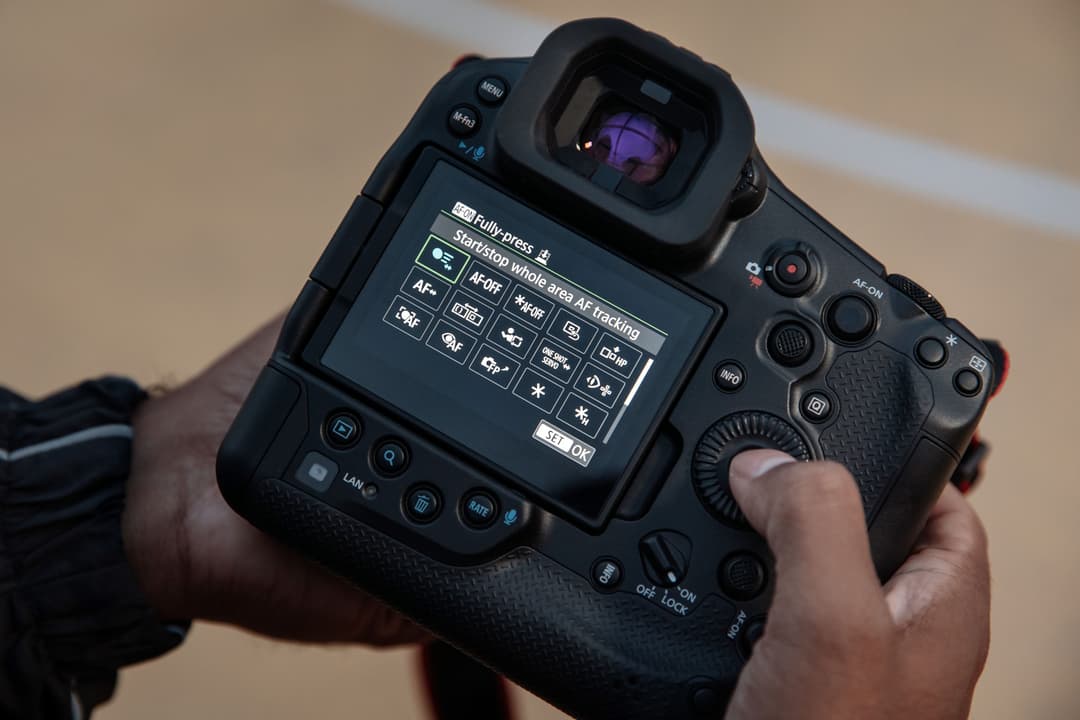 Canon EOS R1 hybride tenu en main, affichant le menu de suivi autofocus sur son écran tactile