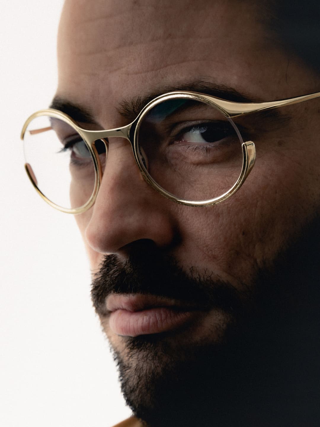Lunettes VISAGES de style rétro à monture dorée et verres ronds, portées par un homme de profil