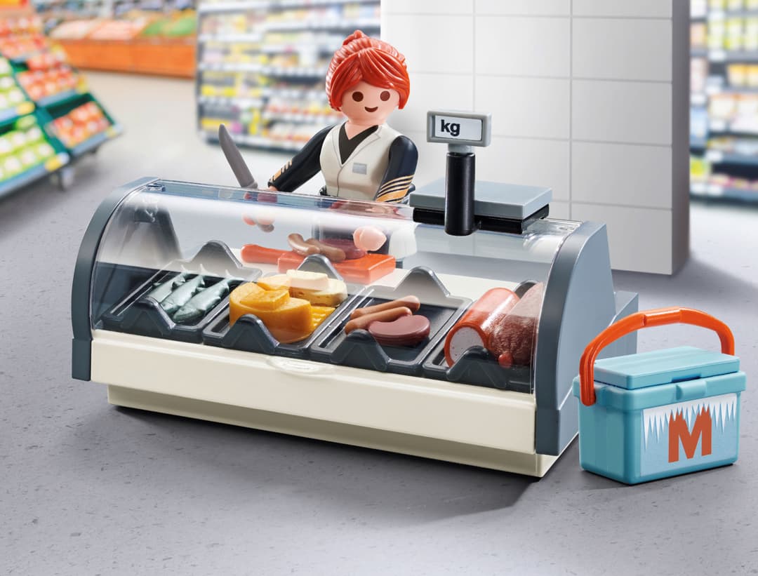 Figurine PLAYMOBIL en caissière au comptoir de charcuterie d'un magasin Migros, avec produits et balance