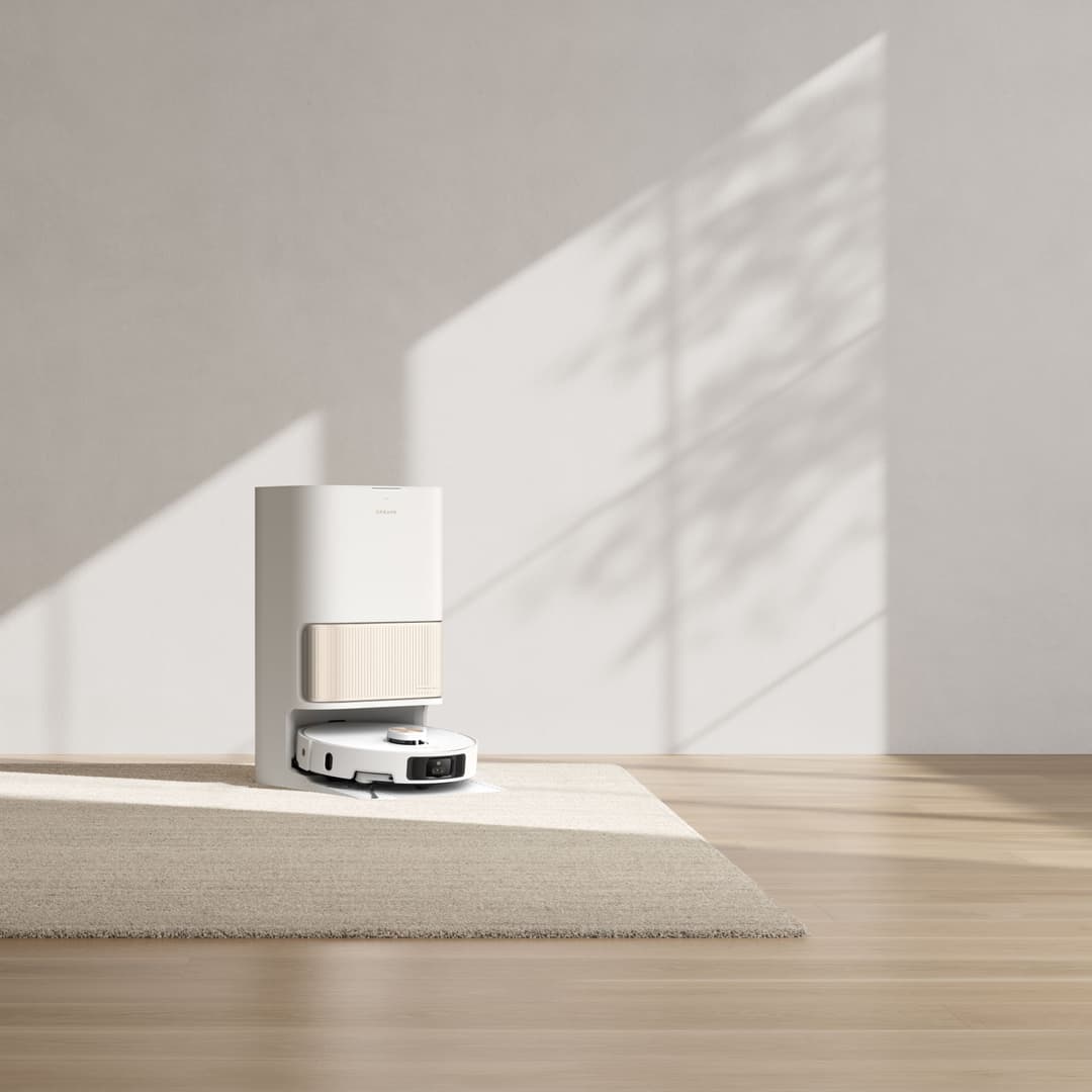 Robot aspirateur laveur Dreame L40 Ultra blanc et noir sur parquet, avec sa station de vidage beige en arrière-plan