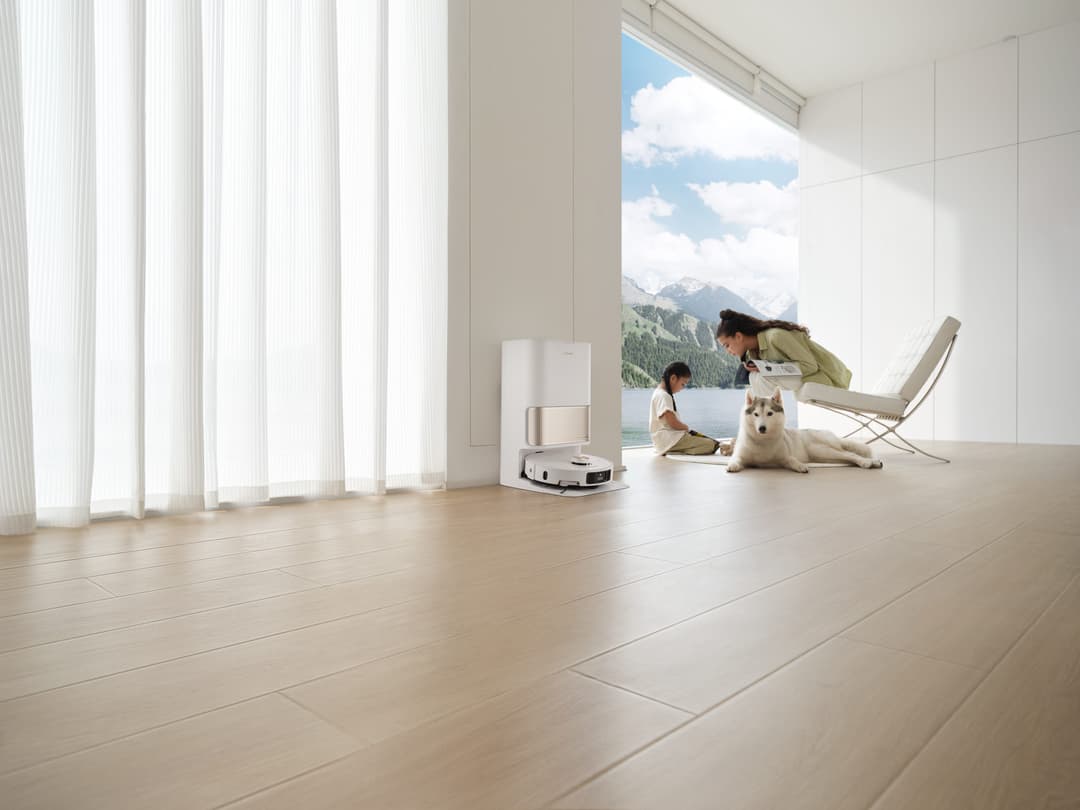 Robot aspirateur et laveur Dreame L40 Ultra blanc avec station de nettoyage dans un salon moderne, vue panoramique montagne
