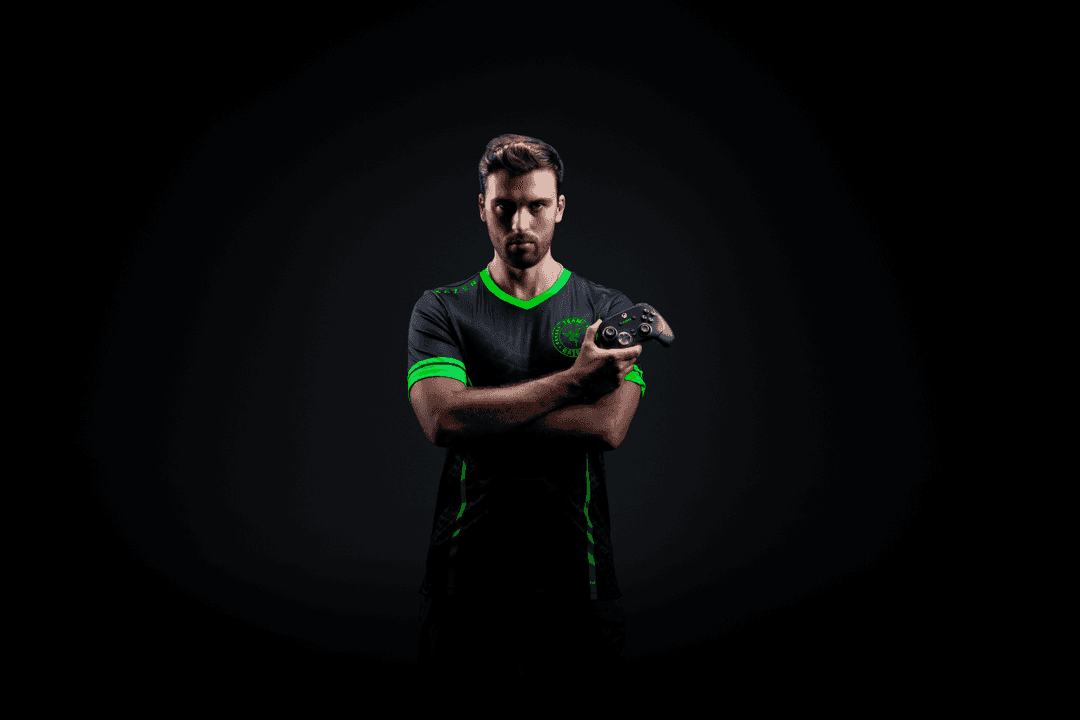Joueur tenant une manette Wolverine V3 Pro noire et grise, portant un t-shirt noir et vert sur fond sombre
