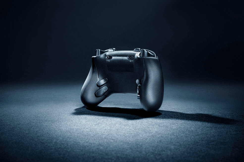 Manette Wolverine V3 Pro de profil, noir avec poignées en caoutchouc texturé et palettes personnalisables à l'arrière, sur fond bleu