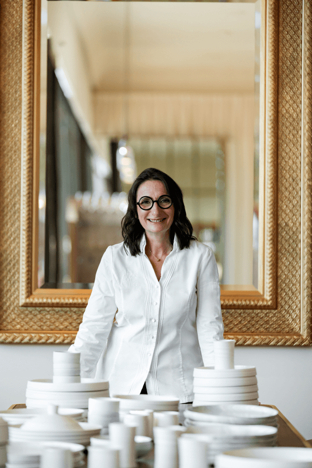 Anne-Sophie Pic dans le Restaurant PIC rénové du Beau-Rivage Palace, entourée de porcelaine blanche, devant des miroirs dorés