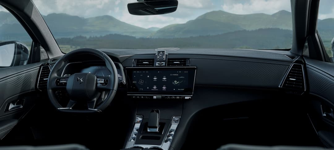 Intérieur noir d'une DS 3 avec volant, écran tactile et montagne visible par la fenêtre