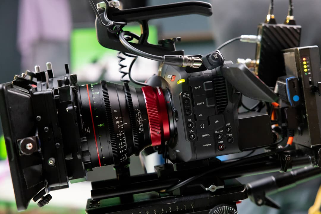 Caméra Canon EOS C80 noire équipée d'un objectif à bague rouge, d'un microphone et d'accessoires de production vidéo professionnelle