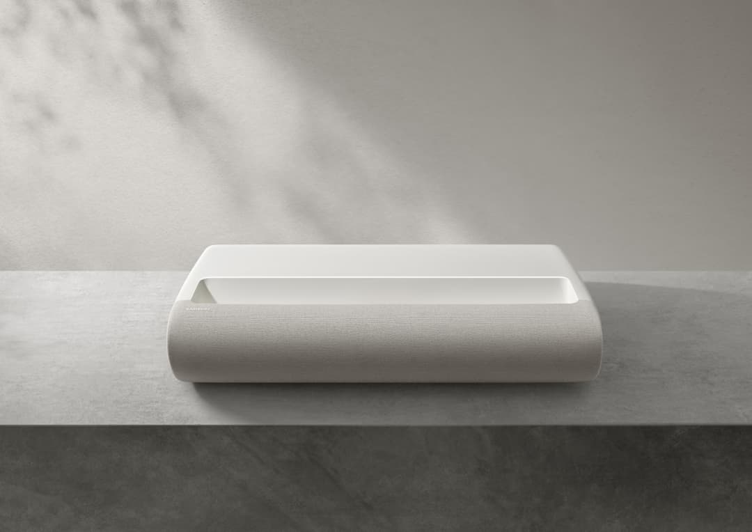 Projecteur Samsung The Premiere blanc de design épuré, en forme cylindrique avec finition textile, posé sur un meuble