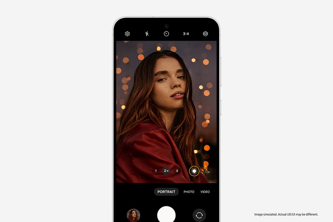 Samsung Galaxy S24 FE affichant une interface de portrait avec selfie en mode studio, femme en pull rouge sur fond bokeh doré