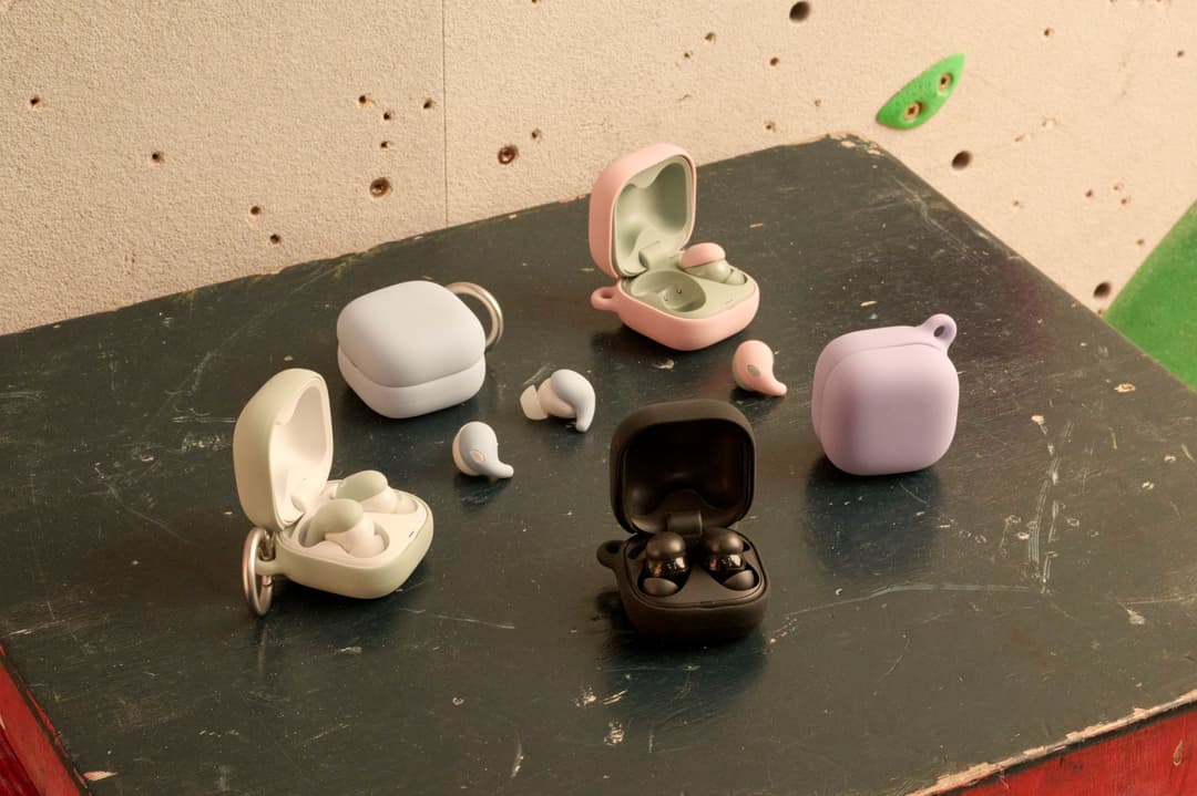 Écouteurs Sony LinkBuds Fit en blanc, rose et noir avec leurs étuis de recharge respectifs, disposés sur une surface noire
