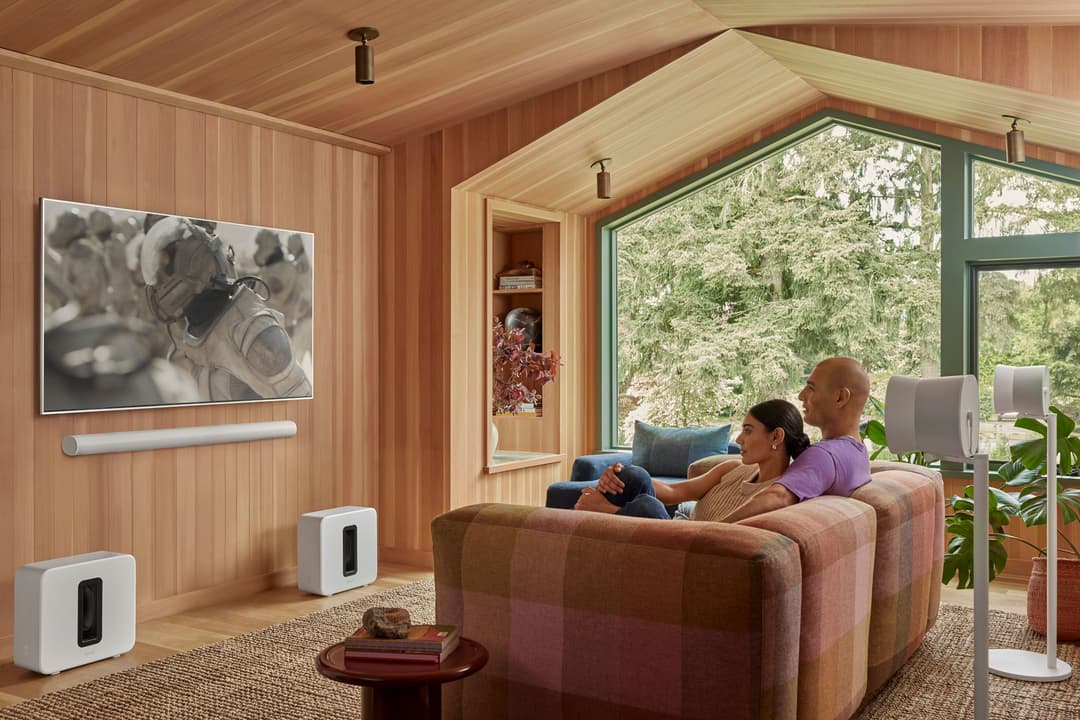 Sonos Arc Ultra, barre de son blanche sous un écran, et Sonos Sub 4, enceinte blanche, dans un salon moderne avec canapé
