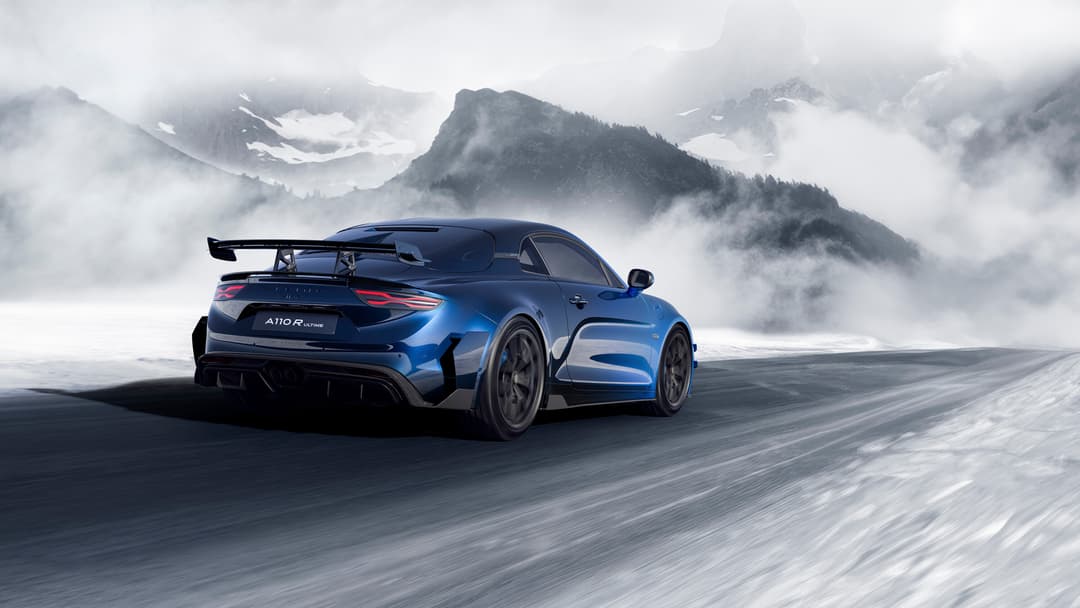 Alpine A110 R Ultime bleu dégradé en mouvement sur route enneigée, montagnes brouillées en arrière-plan