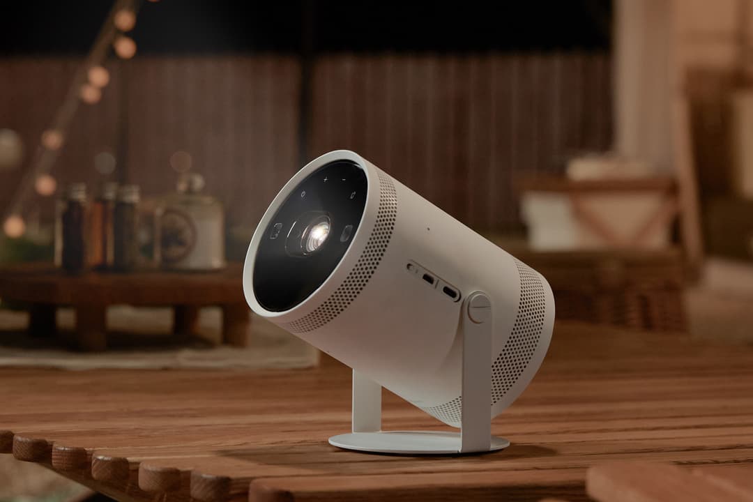 Projecteur Samsung blanc et noir de forme cylindrique posé sur un bureau en bois