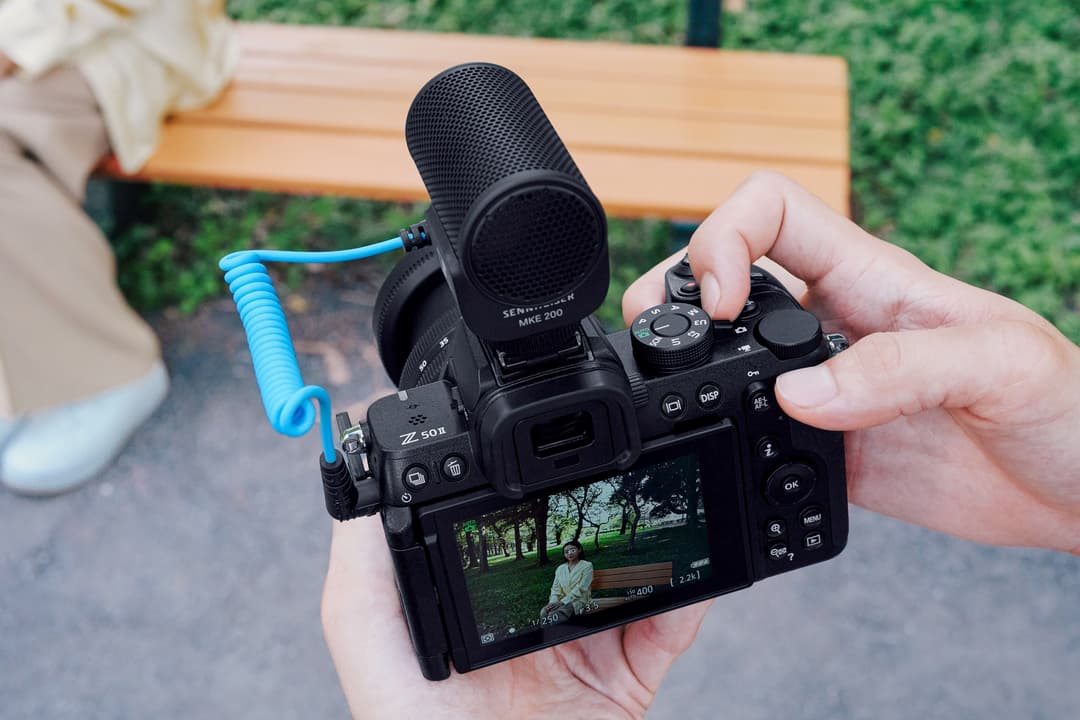 Nikon Z50II tenu en main avec microphone externe bleu et écran LCD affichant une scène de parc