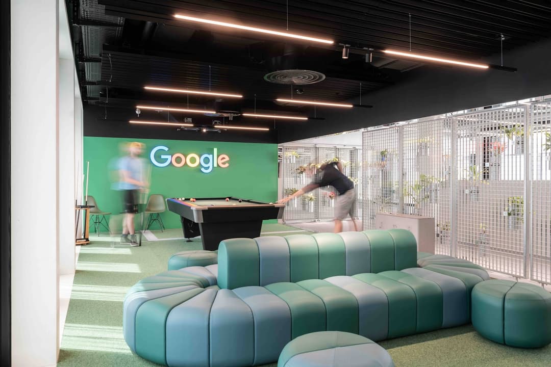 Espace de travail Google à Zurich avec canapés bleus, table de billard et logo Google sur mur vert