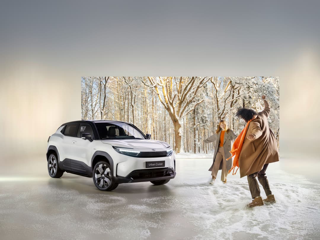 Toyota Urban Cruiser blanc et noir garé dans un paysage enneigé avec trois personnes en manteaux colorés à proximité