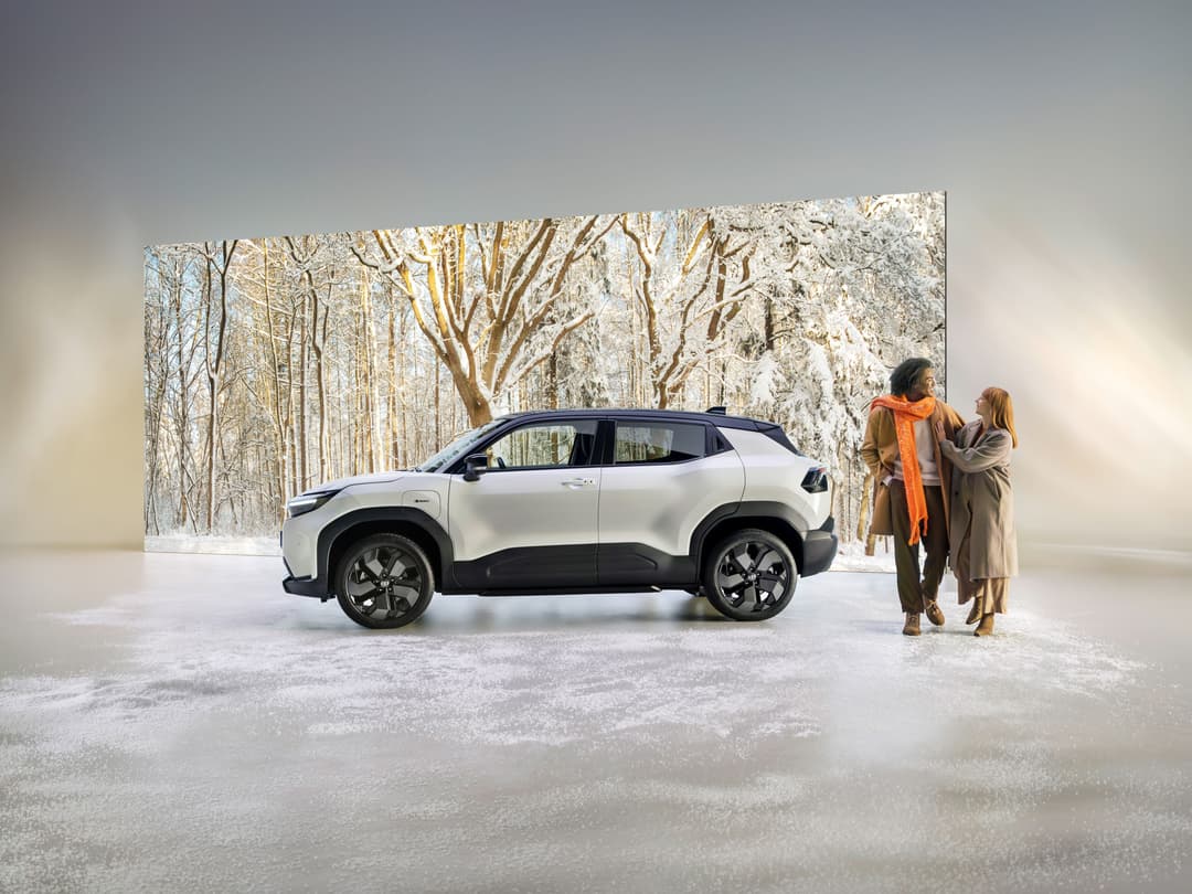 Toyota Urban Cruiser blanc et noir garé en hiver, deux femmes à proximité observant le véhicule électrique