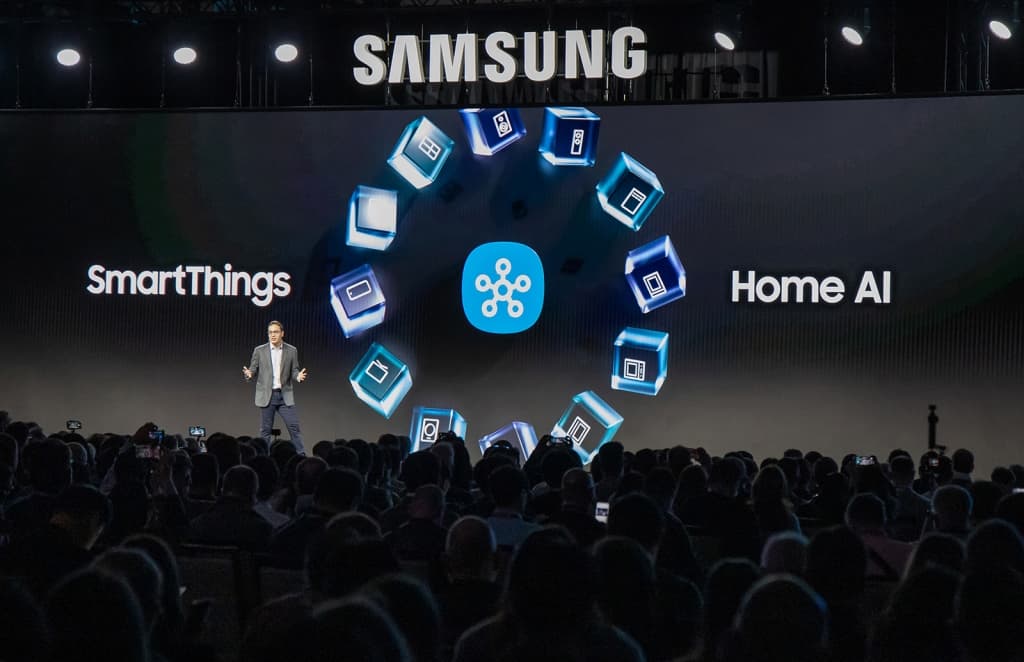 Présentateur Samsung sur scène au CES, écran affichant SmartThings et Home AI avec icônes d'appareils connectés bleu et blanc