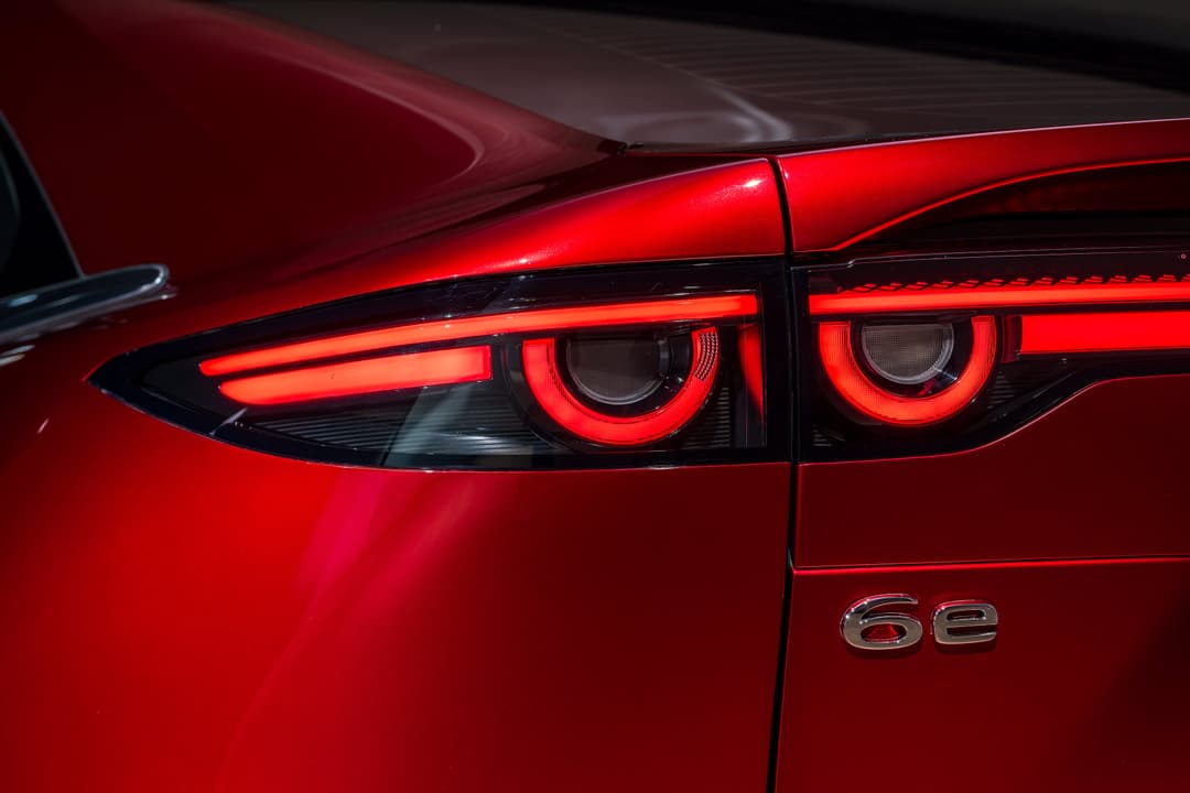 Mazda6e rouge avec feux arrière LED allumés, badgeé 6e sur la carrosserie