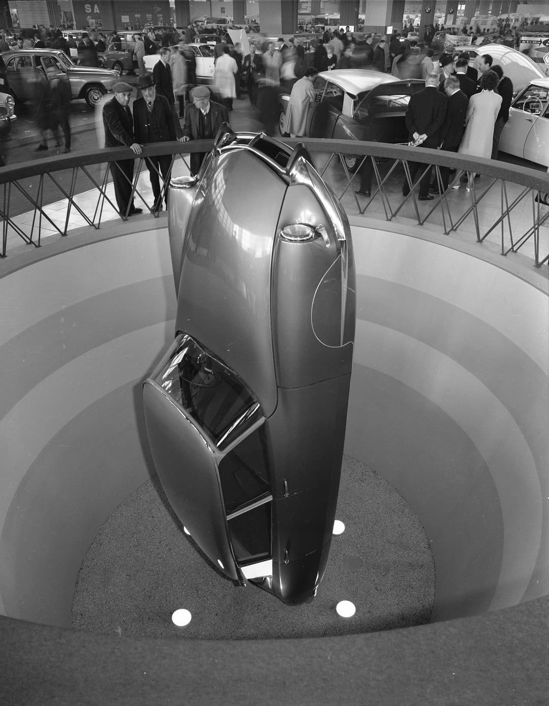 DS verticale présentée dans une fosse circulaire lors d'une exposition automobile, visiteurs observant depuis une passerelle
