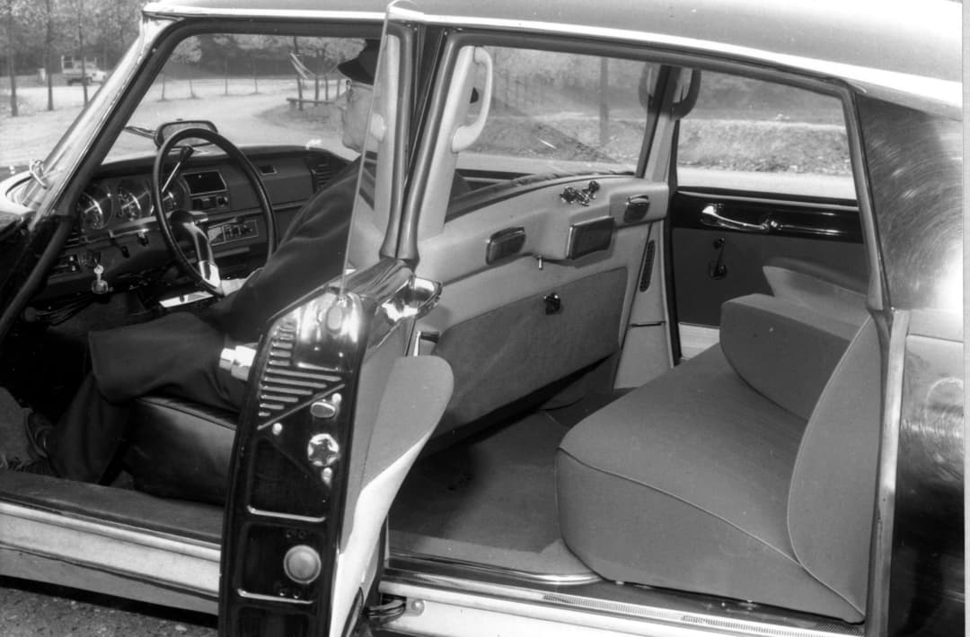 Intérieur spacieux d'une DS avec portières ouvertes, montrant le volant, le tableau de bord et les sièges confortables années 1960