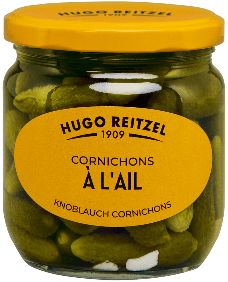 Pot de cornichons à l'ail Hugo Reitzel 1909 avec couvercle jaune et étiquette jaune, contenant des cornichons verts