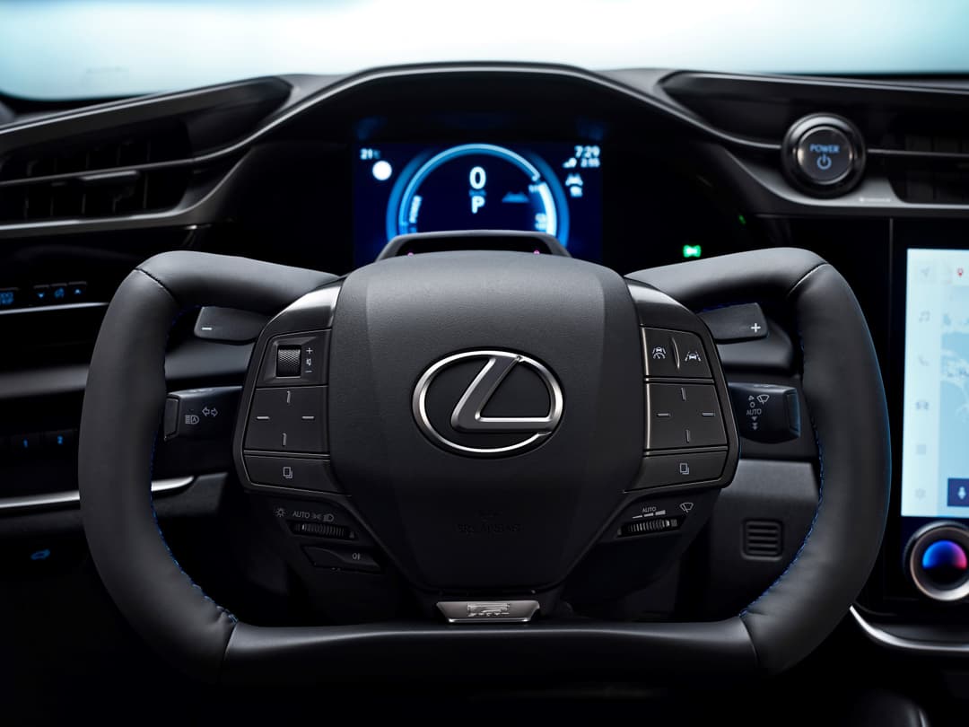 Intérieur du Lexus RZ 2025 avec volant F SPORT noir, tableau de bord numérique bleu et accents de surpiqûres bleues