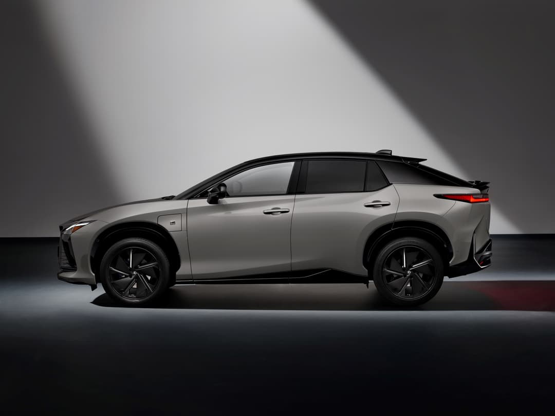 Lexus RZ 2025 de couleur grise, présenté de profil dans un studio avec éclairage dramatique
