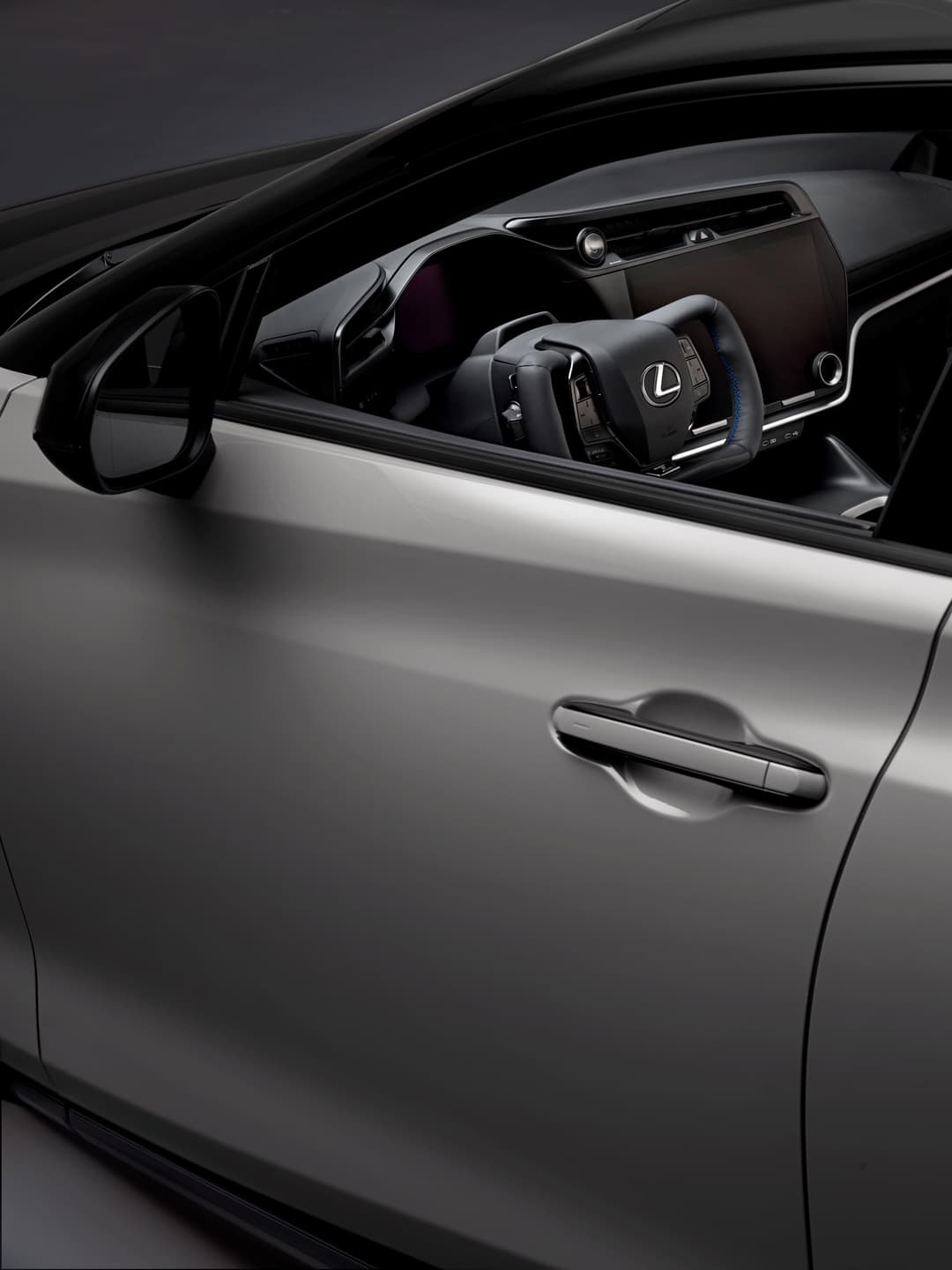Intérieur du nouveau Lexus RZ 2025 avec volant et tableau de bord modernes, vue de côté avec portière ouverte