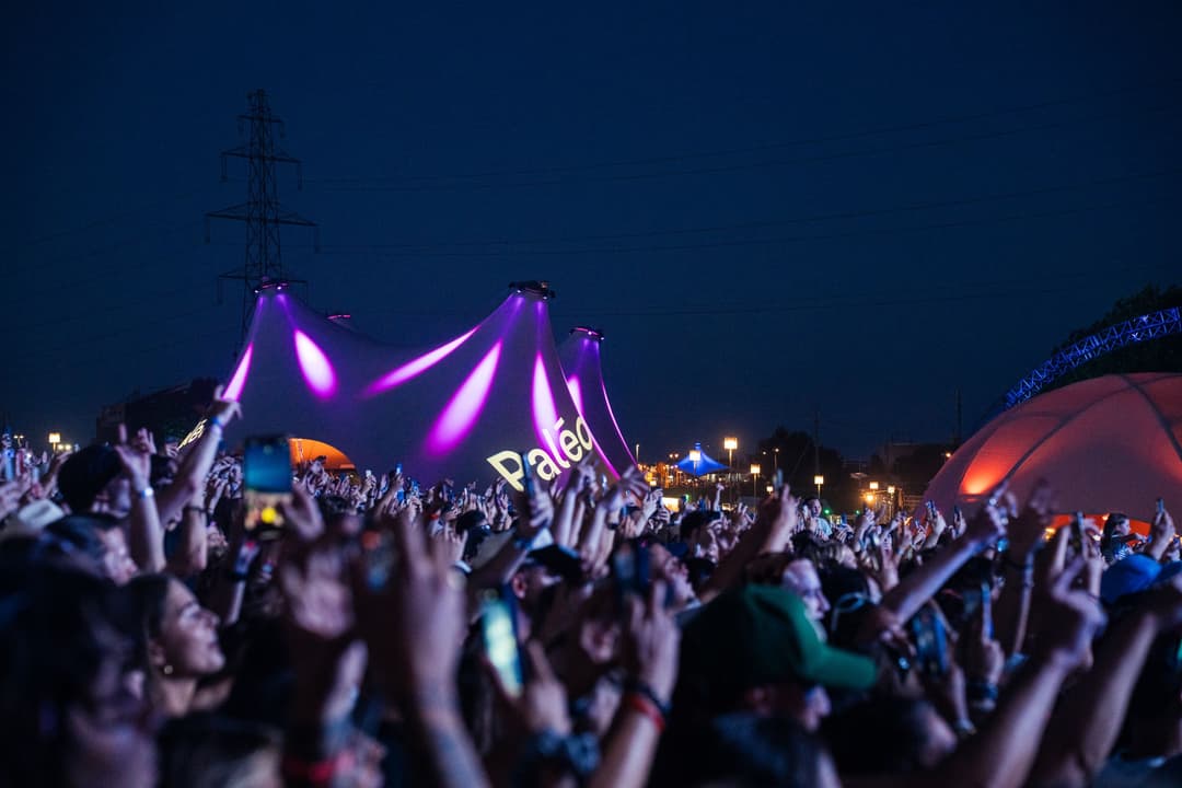 Scène du Paléo avec structures gonflables violettes illuminées et foule de spectateurs levant les bras en pleine nuit