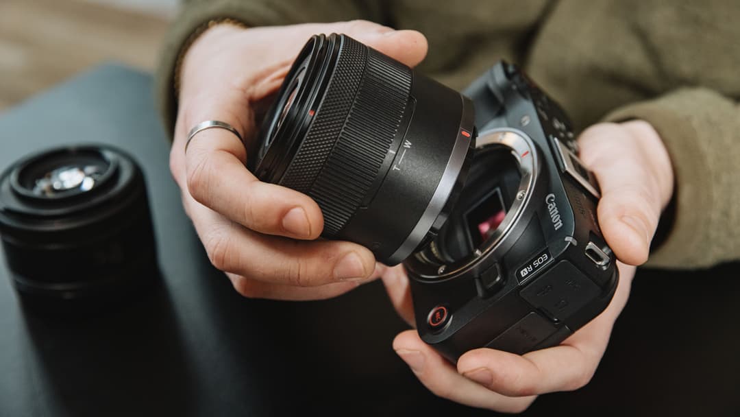 Objectif Canon noir compact tenu dans les mains, avec zoom contrôlable et port de filtres 58 mm