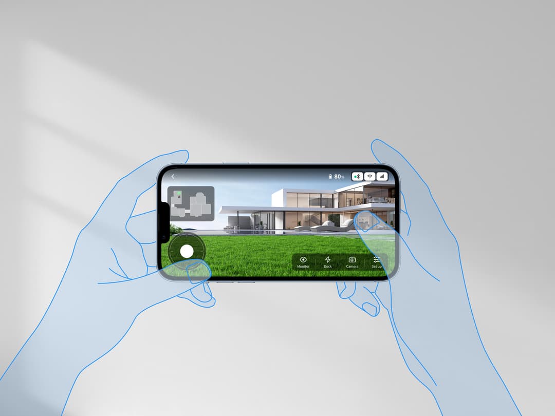 Mains tenant un smartphone affichant la surveillance en temps réel d'un jardin avec une maison, pelouse et options de contrôle